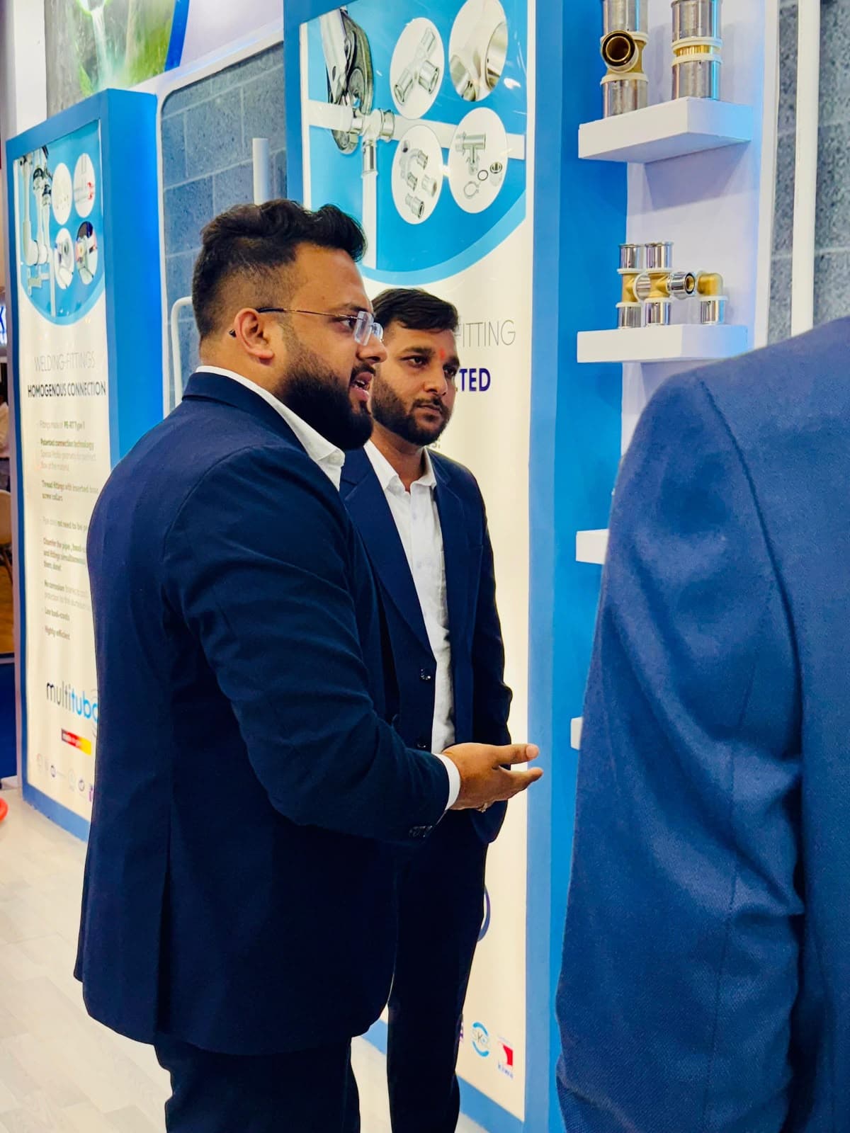 Multitubo representatives discussing welding fittings with a visitor at the exhibition